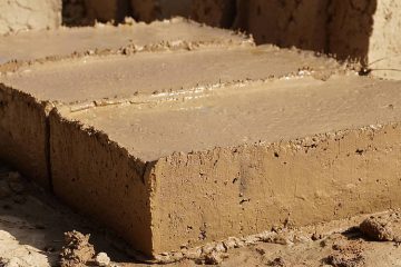 Frisch geformte Lehmziegel liegen zum Trocknen auf dem Boden