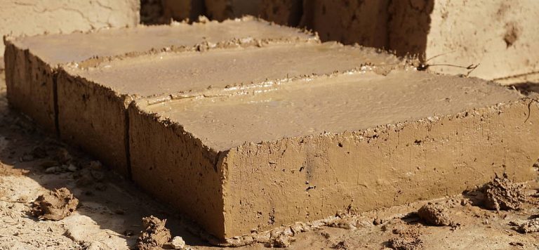 Frisch geformte Lehmziegel liegen zum Trocknen auf dem Boden